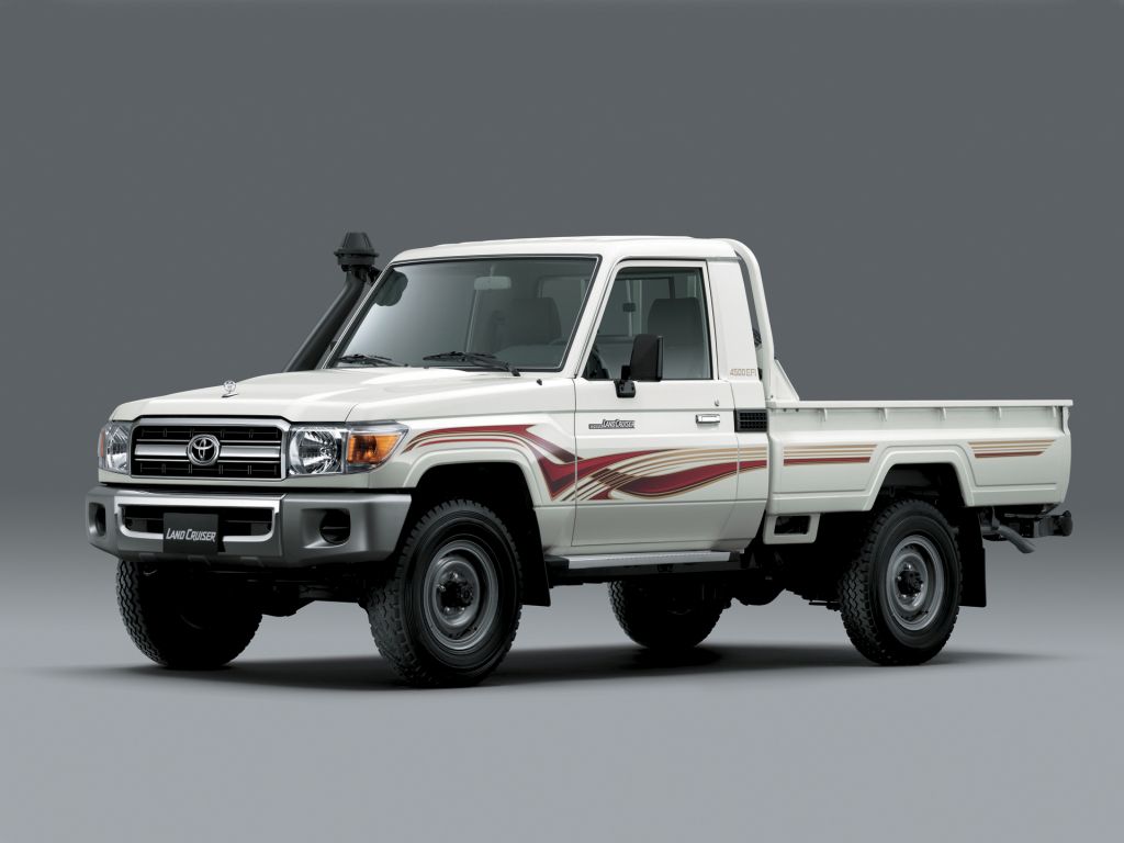 White Toyota Land Cruiser 70 Series single-cab pickup truck with snorkel and side stripes, front three-quarter studio view — classic 4x4 imported into Canada under the 15-year exemption and sourced to order by Seaver Associates Inc.
