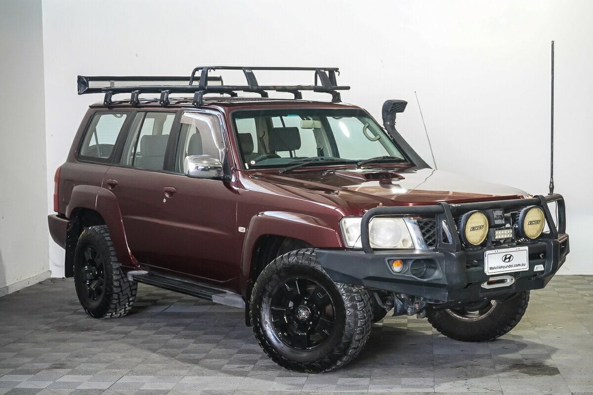 Maroon Nissan Patrol Y61 4x4 wagon with bull bar, driving lights, snorkel and roof rack in a showroom — example of the Nissan Patrol models Seaver Associates sources to order